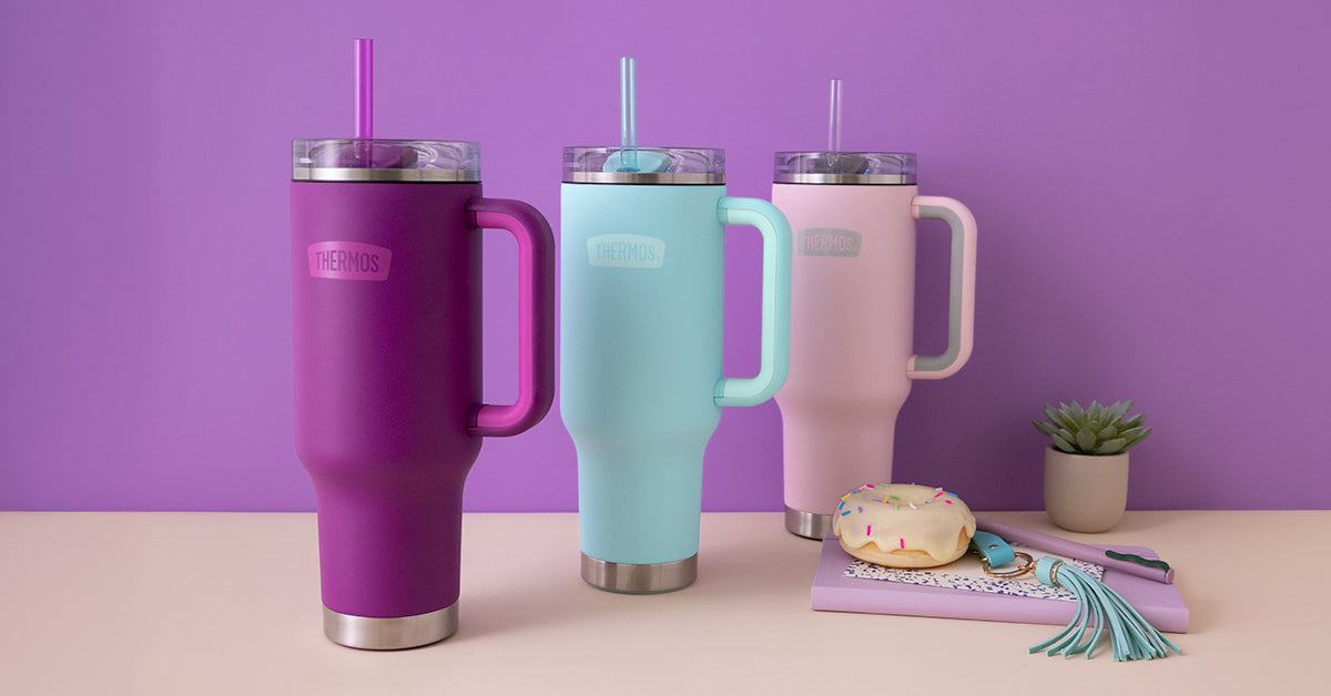 Three insulated 40oz travel mugs in purple, blue, and pink on a table with a purple background.
